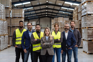 Full team of warehouse employees standing in warehouse. Team of workers, managers, female director in modern industrial factory, heavy industry, manufactrury. Full team of warehouse employees standing in warehouse. Team of workers, managers and female director in modern industrial factory, heavy industry, manufactrury.