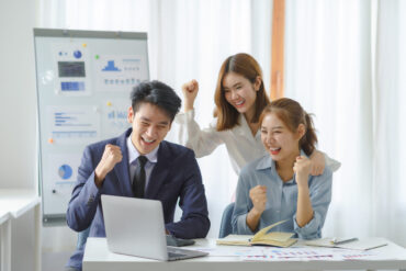 Successful group of young Asian business people achieving goals Successful group of young Asian business people achieving goals excited raised hands rejoicing. New startup project concept.