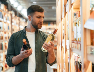 Front view. Man is choosing wine in the store Front view. Man is choosing wine in the store